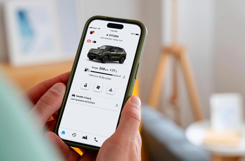 Person holding a smartphone displaying a car monitoring app interface.