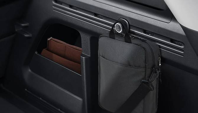 Black bag hanging in a car interior next to a compartment with brown folders.