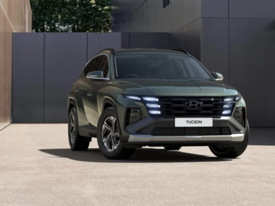 Green Hyundai Tucson car in front of a building.