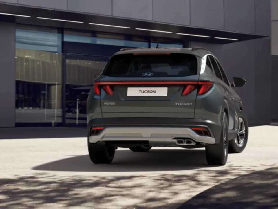 Rear view of a grey Hyundai Tucson parked outside a modern building.
