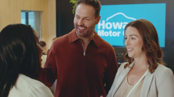 Three people in a showroom, two are shaking hands and smiling.