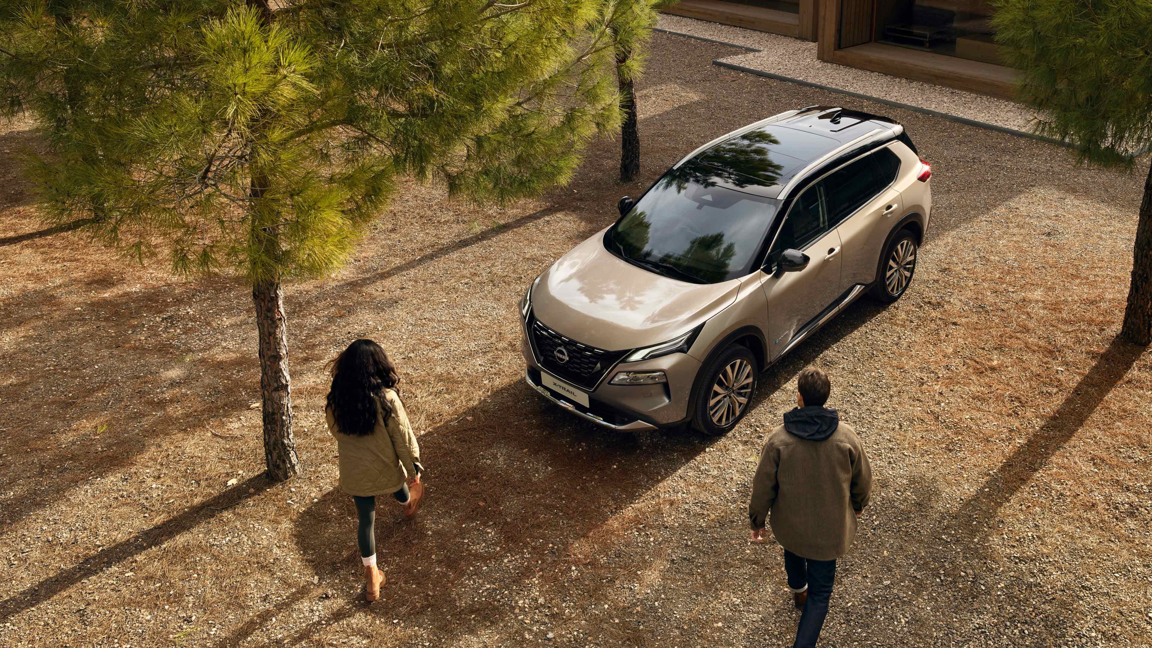 Two people walking towards a parked SUV among trees.