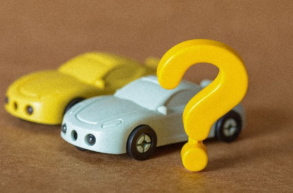 Two toy cars, yellow and blue, with a large yellow question mark in front.