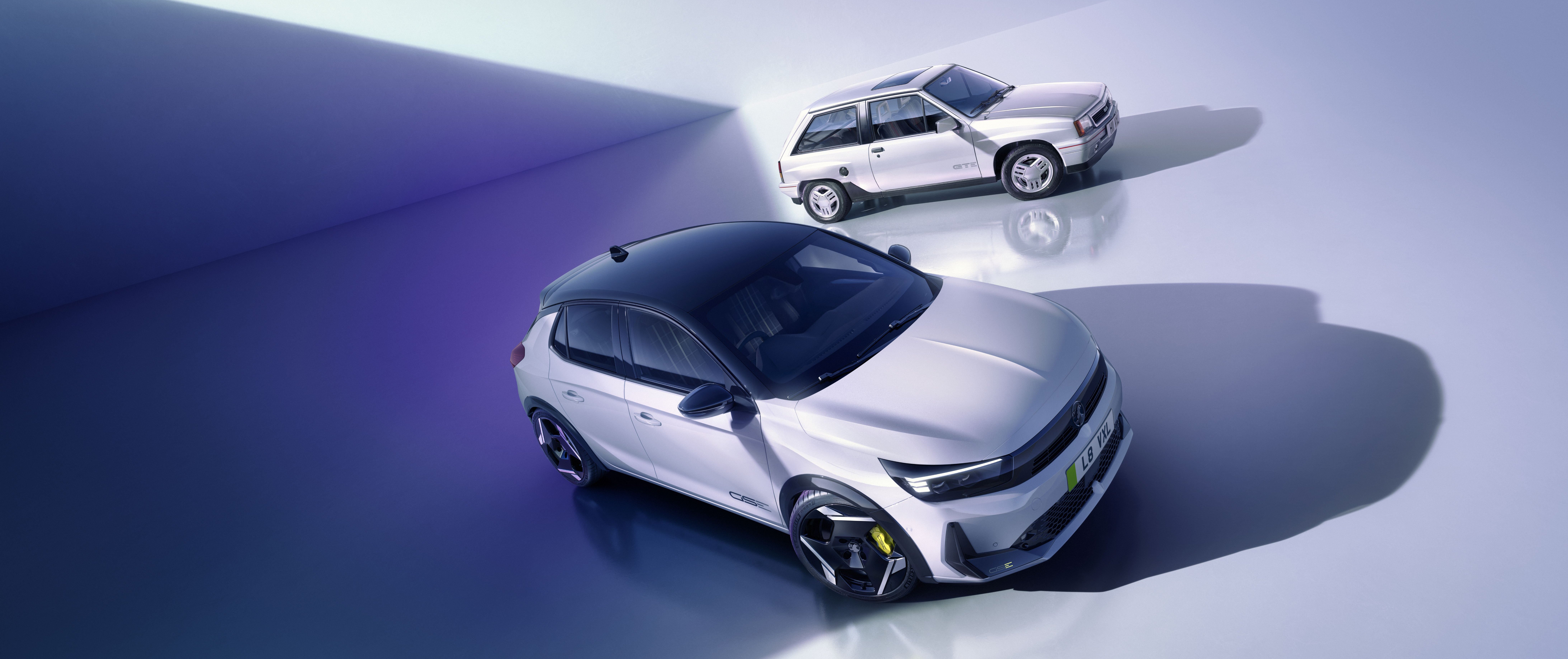 Two white cars, one modern and one classic, positioned in a studio setting.