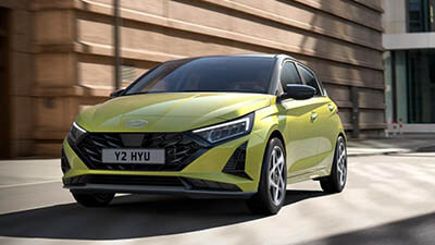 A bright green hatchback car driving on a city street.