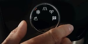 Close-up of a hand adjusting a car's drive mode selector with various symbols.