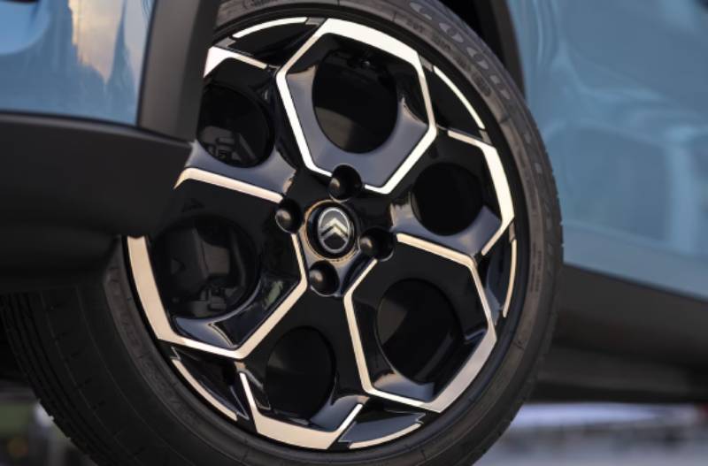 Close-up of a Citroën car wheel with a black and silver hexagonal alloy design.