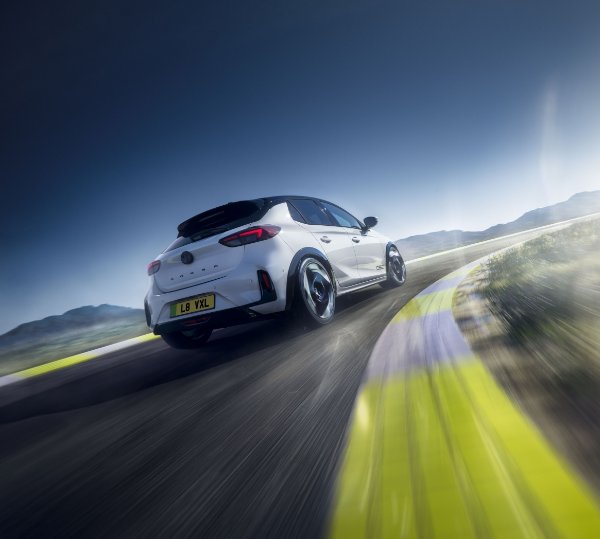 White car driving on a winding road at high speed.