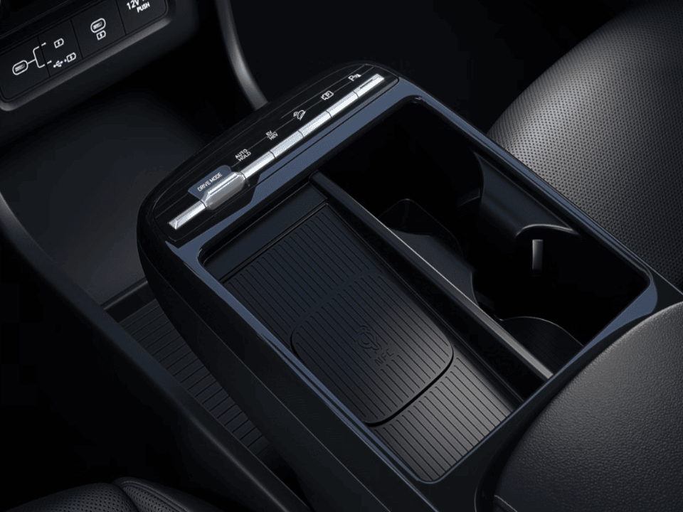 Car centre console with drive mode buttons, wireless charging pad, and cup holder.
