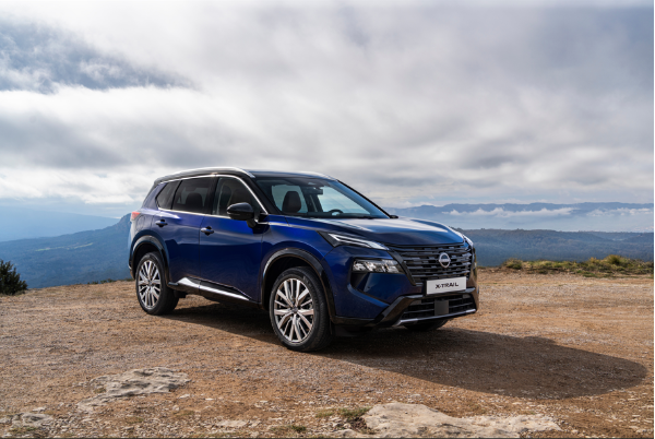 Blue SUV parked on a dirt road with distant mountainous view under a cloudy sky.