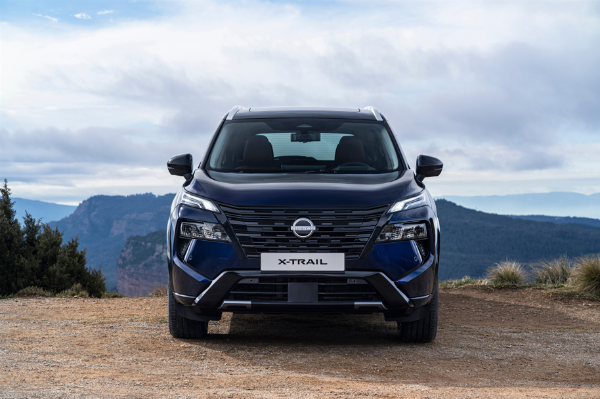 Front view of a blue Nissan X-Trail SUV on a dirt track.