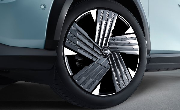 Close-up of a car wheel with a unique alloy design and a Nissan logo in the centre.
